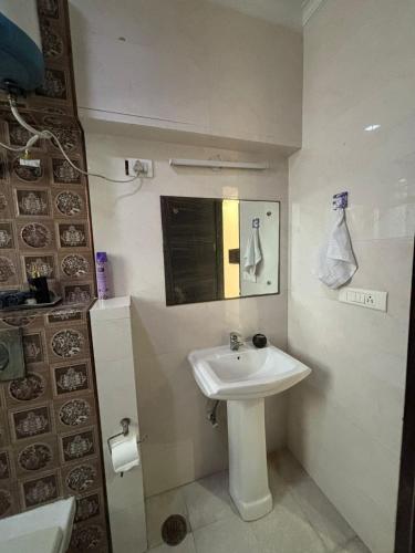 a bathroom with a white sink and a mirror at Sarla Residency in Noida