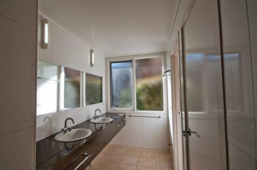 uma casa de banho com 2 lavatórios e uma cabina de duche ao nível do chão em Pelicans Perch em Lake Tyers
