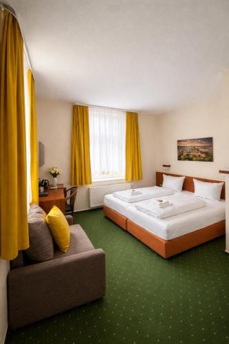 a hotel room with two beds and a couch at REGIOHOTEL Bunte Stadt Wernigerode in Wernigerode