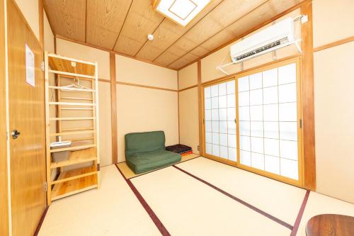 a room with a green chair and a window at May Guest House in Tokyo