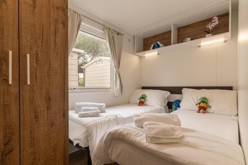 a bedroom with two beds with white sheets and a window at Club del Sole Marina Family Resort in Punta Marina
