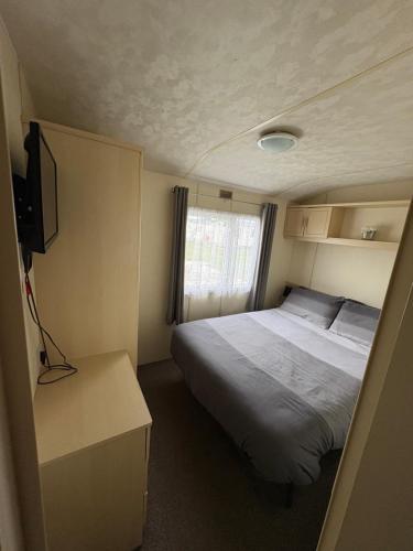 a small bedroom with a bed and a television at Golden Palm Resort Meadow Lakes 3 bedroom 8 berth in Chapel Saint Leonards