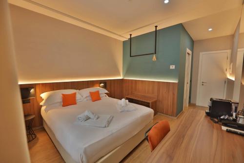 ein Schlafzimmer mit einem großen weißen Bett und orangefarbenen Kissen in der Unterkunft Moody smart & comfy Hotel in Terranuova Bracciolini