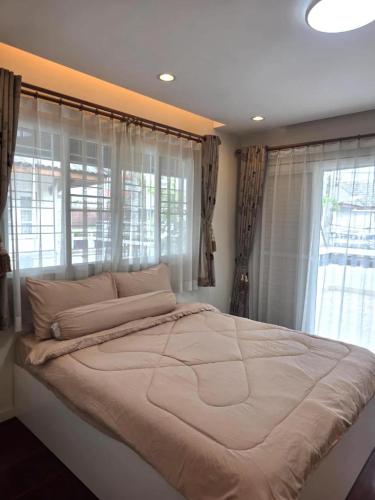 a large bed in a bedroom with a large window at Sugar Beach Villa Bangsaen in Ban Bang Saen (1)