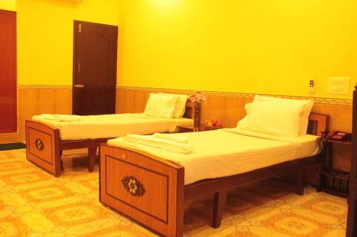 two beds in a room with yellow walls at Chettinaadu Narayana Vilas in Kānādukāttān