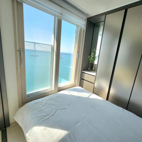 a bedroom with a bed and a large window at Busan#Gwanganli#Hot place#Healing Home in Busan