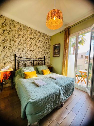 a bedroom with a bed with a green comforter at Hotel Le Ponteil in Antibes