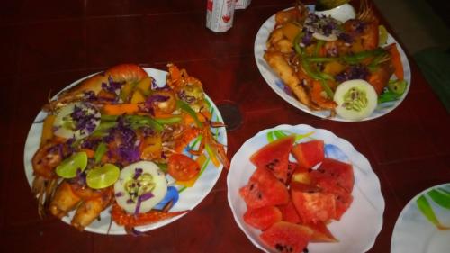 three plates of food on a wooden table at Nilaveli Beach Rooms in Nilaveli