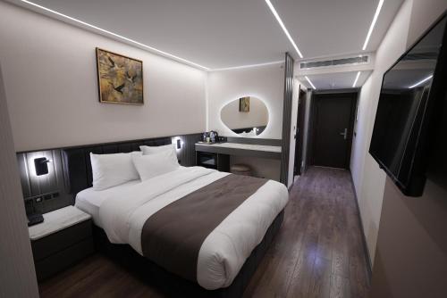 ein Hotelzimmer mit einem großen Bett und einem Spiegel in der Unterkunft The Nava Hotel in Bostaniçi