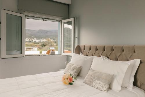 a bedroom with a bed with white pillows and a window at Meltemi Beach Apartments 2 in Milatos