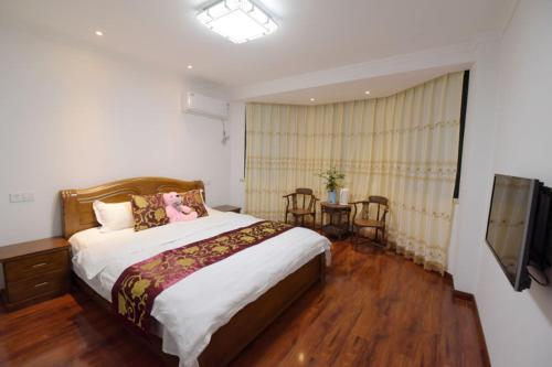 a bedroom with a bed and a table and a television at Tianmuhu Tianyuege Villa in Liyang