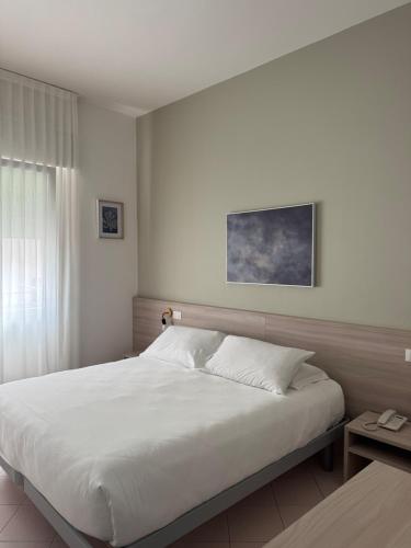 a bedroom with a large white bed and a table at Hotel Ammare in Sottomarina