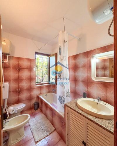 a bathroom with a sink and a tub and a toilet at Sardegna 20 in San Teodoro