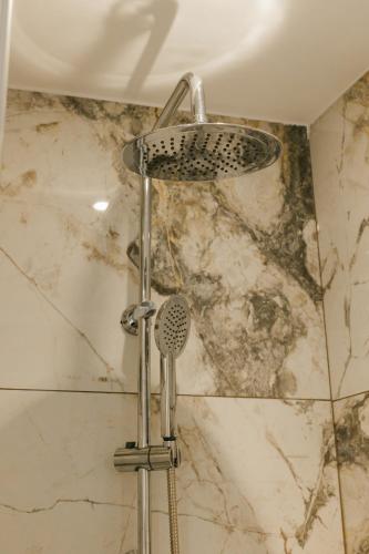 a shower in a bathroom with a marble wall at Meltemi Beach Apartments 2 in Milatos