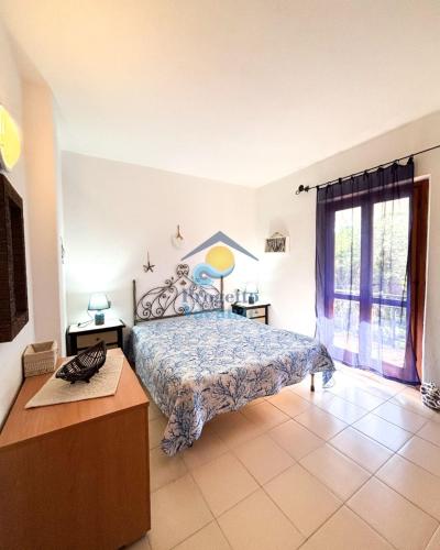 a bedroom with a bed and a table and a window at Sardegna 20 in San Teodoro