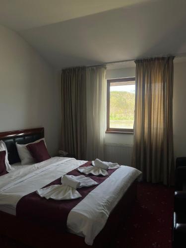 ein Schlafzimmer mit einem großen Bett mit weißer Bettwäsche und einem Fenster in der Unterkunft Hotel Ostrov in Călimăneşti
