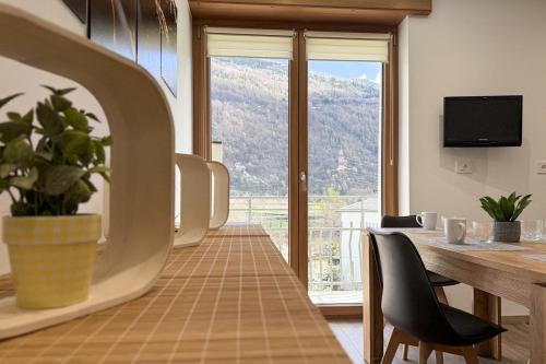 a dining room with a table and a large window at Alla Rupe 8 - bilocale con vista sulle Alpi in Grosotto