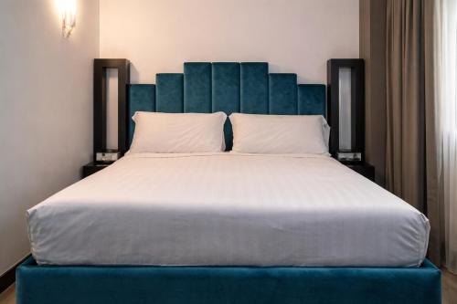 a bedroom with a large bed with a blue headboard at Hotiday Napoli Porto in Naples