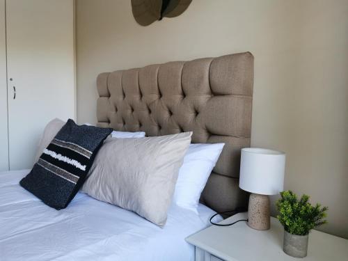 a bed with a pillow and a lamp on a table at The Boho Suite in Benoni