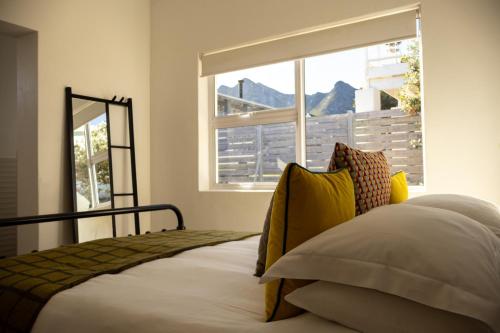 a bedroom with a bed with yellow pillows and a window at Seafront house with a view in Kleinmond