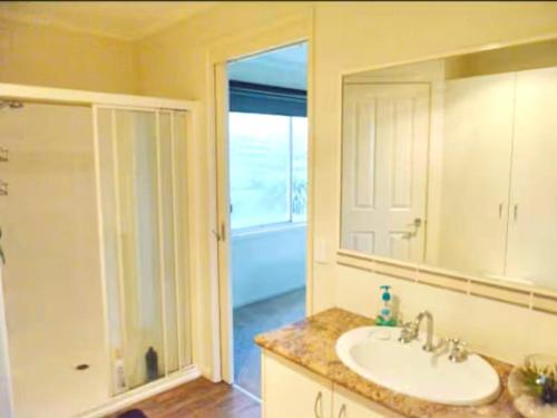 a bathroom with a sink and a shower and a mirror at Oak Hill Cottage - Chirnside Park in Wonga Park