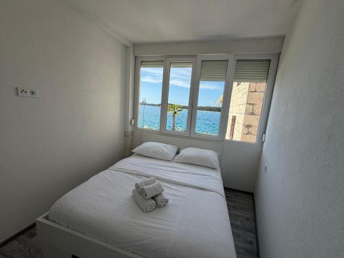 a small bedroom with a bed with a window at Apartman Cezar2 in Rogoznica