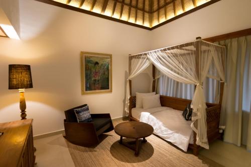 a bedroom with a canopy bed and a chair at Ulun Ubud Resort - CHSE Certified in Ubud