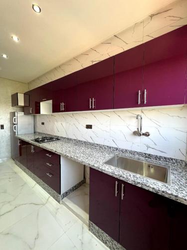a kitchen with purple cabinets and a sink at Appartements ELKHAIR in Tahannout