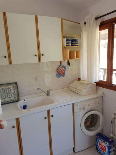 a kitchen with a sink and a washing machine at Airy and cosy summer flat in Siviri