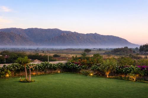 a garden with a green lawn with mountains in the background at Merriment Luxury Resort & Private Pool Villa Near Mount Abu, Abu Road in Bhīmānia