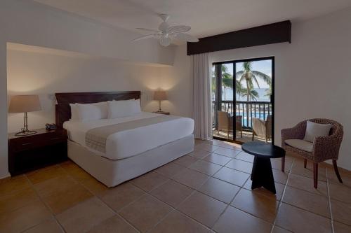 a bedroom with a white bed and a balcony at Catalonia Riviera Maya Resort & Spa- All Inclusive in Puerto Aventuras