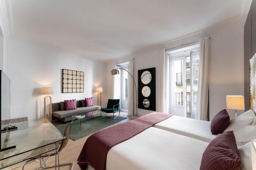 a bedroom with a large bed and a living room at Suite Prado in Madrid