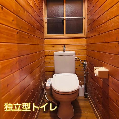 a wooden bathroom with a toilet and a window at 一棟貸し宿月灯草津 in Kusatsu