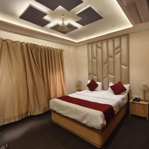 a bedroom with a large bed with red pillows at Sienna Suites in Navi Mumbai