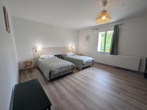 a bedroom with two beds and a table and a window at Graine in Dommartin-le-Franc