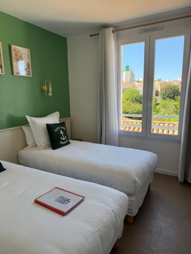 two beds in a hotel room with a window at Atlantic Hôtel - L'Ile d'Yeu in L'Ile d'Yeu