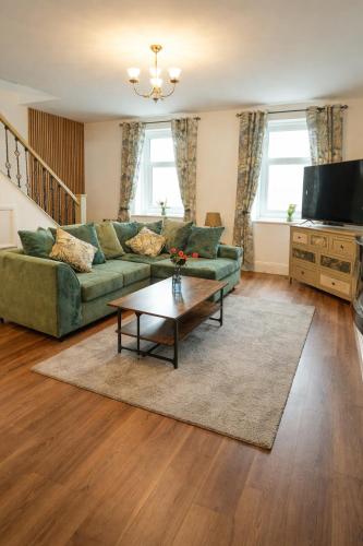 a living room with a green couch and a coffee table at Cambois beach Maisonette with sea view! in Cambois