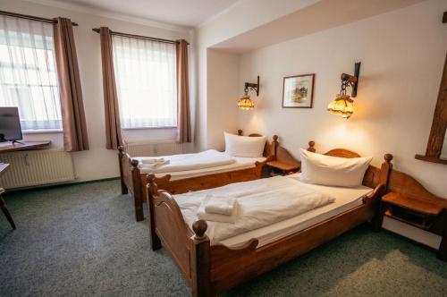 two beds in a room with two windows at REGIOHOTEL Wolmirstedter Hof in Wolmirstedt