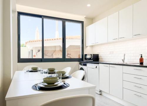 a kitchen with white cabinets and a table with dishes on it at Loulé Sunny Retreat by LovelyStay in Loulé