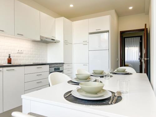 a white kitchen with a table with dishes on it at Loulé Sunny Retreat by LovelyStay in Loulé