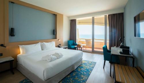 a hotel room with a large bed and a balcony at Occidental Sharjah Grand in Sharjah