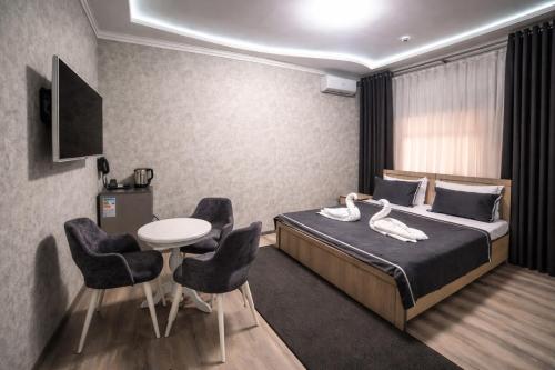 a hotel room with a bed and a table and chairs at Hotel Madera in Tashkent