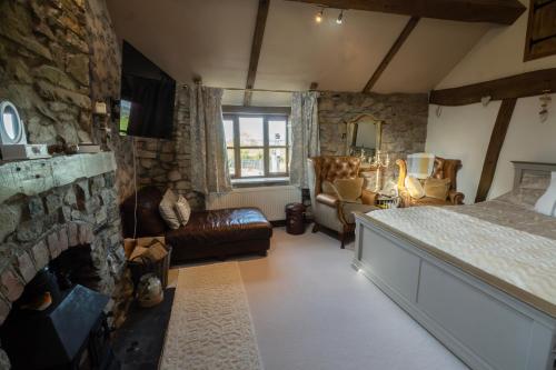 a bedroom with a fireplace and a bed and a stone wall at The Stables Inn in Minsterley