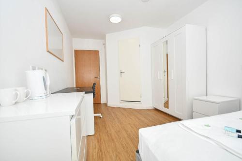 a white kitchen with white cabinets and a wooden floor at Budget En-suites Optional Kitchen Liverpool in Liverpool