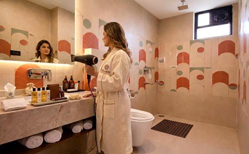 a woman standing in a bathroom blow drying her hair at Valmere Chery Blossom Suites in Shillong