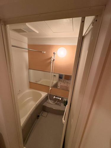 a bathroom with a tub and a sink and a toilet at Hana Hostel Fujisan Apartment in Fujiyoshida
