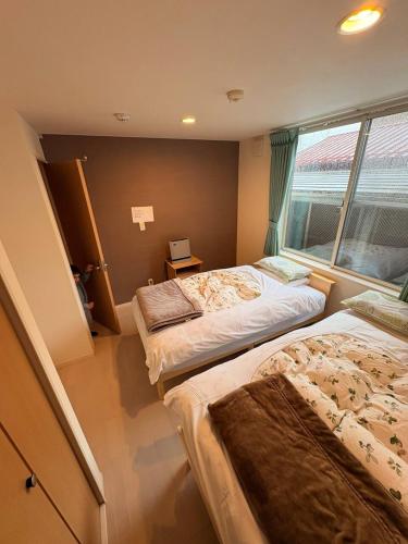 two beds in a room with a window at Hana Hostel Fujisan Apartment in Fujiyoshida