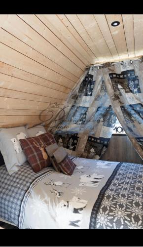 a bed in a room with a wooden ceiling at L écureuil in Granges-Aumontzey
