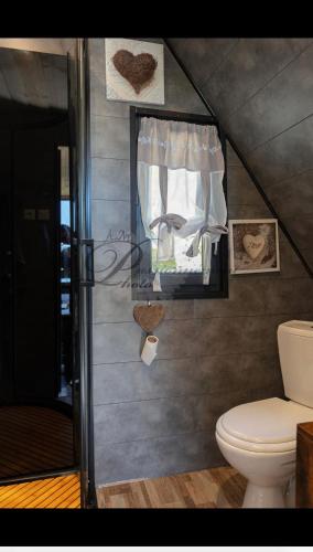a bathroom with a toilet and some pictures on the wall at L écureuil in Granges-Aumontzey