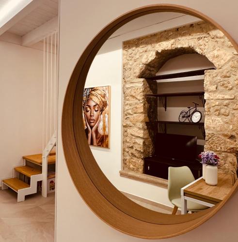 a circular mirror hangs on a wall in a living room at Eureka Apartment in Noto